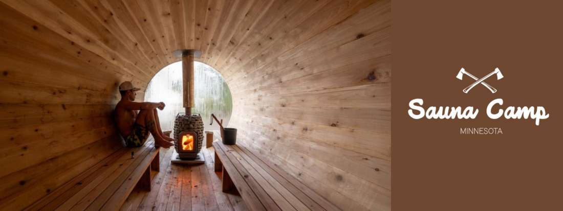 A man sits inside a round wooden sauna